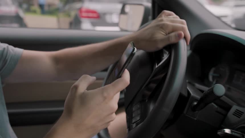 The man uses his cell phone while driving