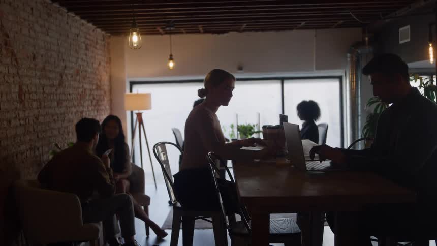 People chat and work under warm lighting inside a cozy cafe