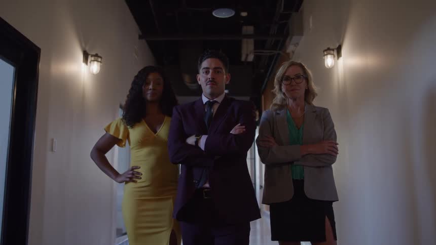 Three professionals walk together down a hallway with confident expressions