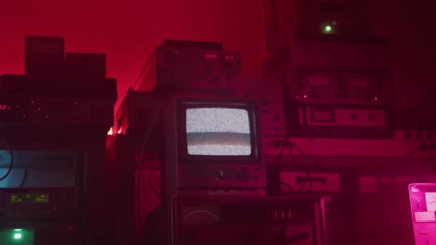 Old television displays static in a room lit by red light
