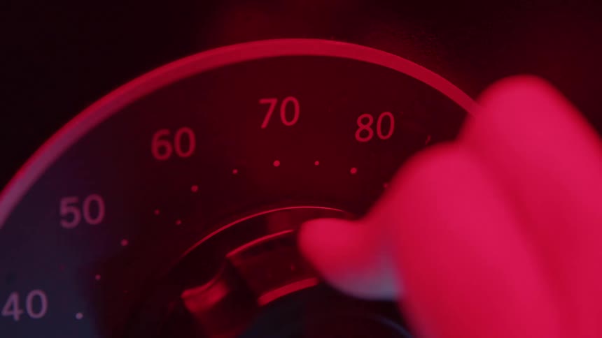 A person turns a knob to the number eighty