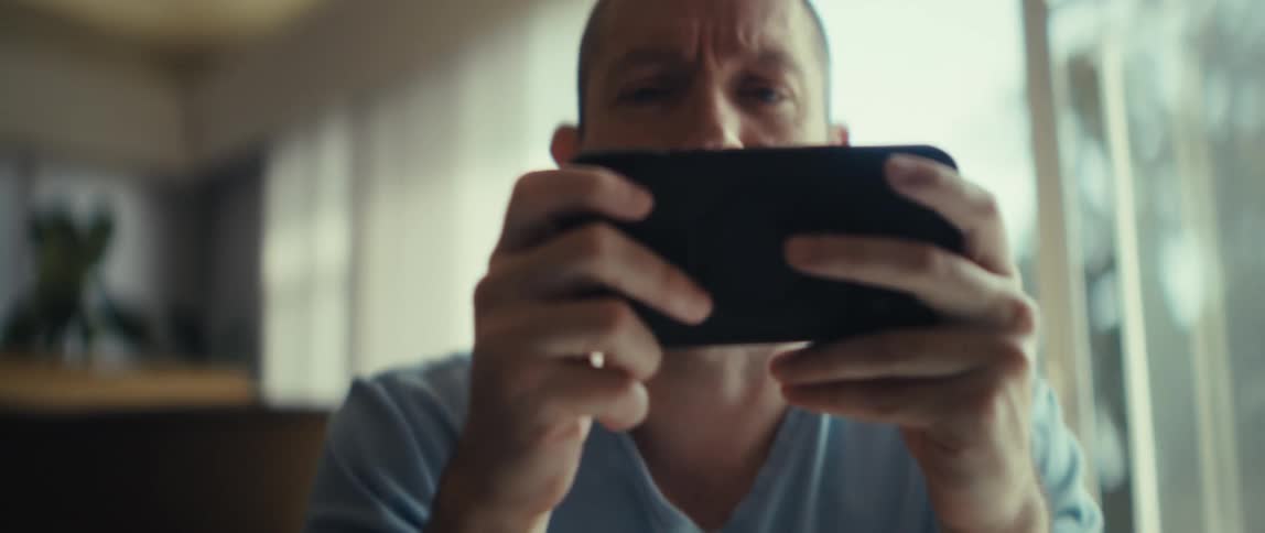 A man is sitting inside looking at his cellphone