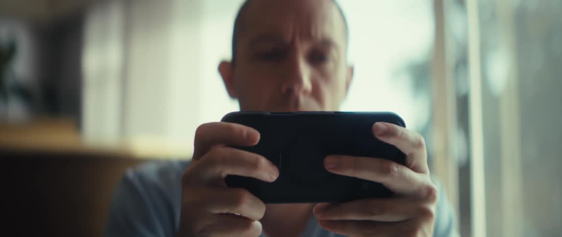 Young man sitting down indoors using a smartphone during day time