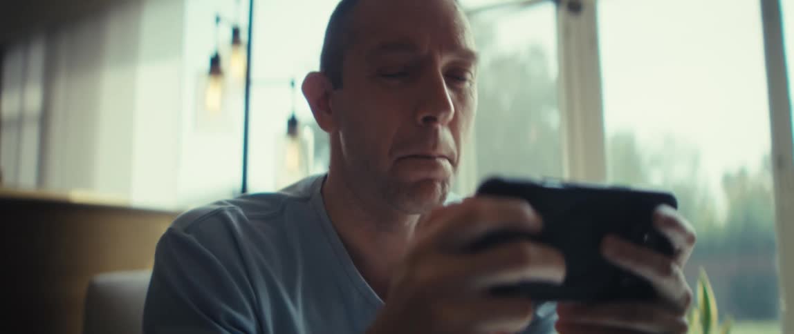 Man holding a smartphone with both hands indoors