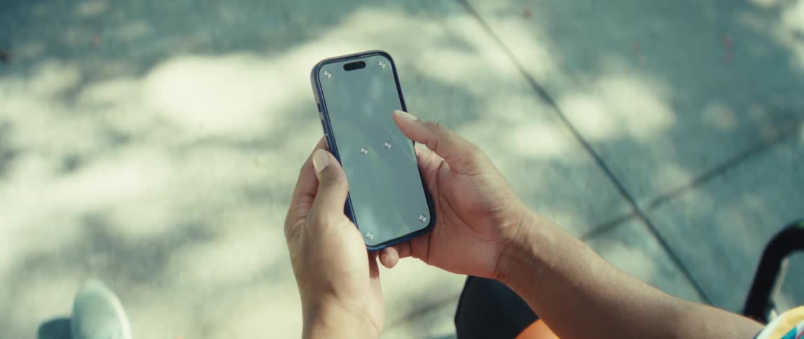 Man holds his phone while looking at the screen under sunlight