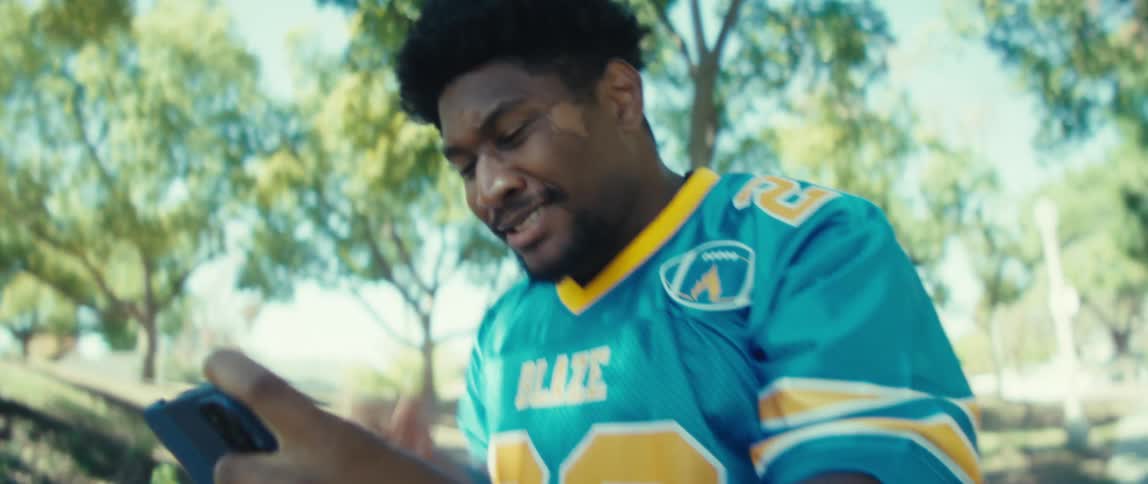 Man celebrates excitedly while looking at his phone outdoors