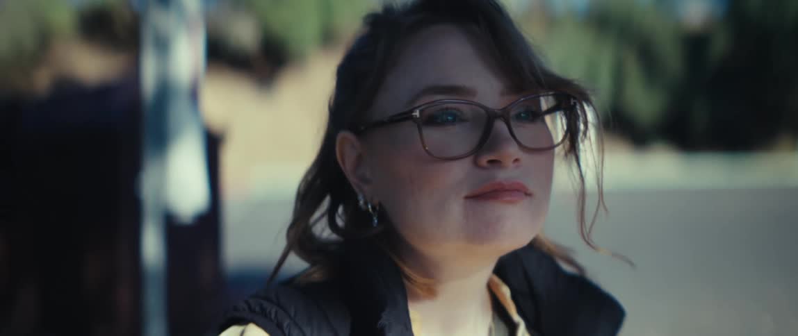 Woman with glasses looks toward the horizon under sunlight