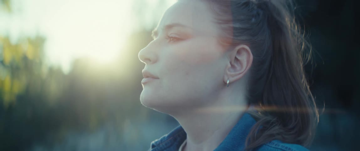 Woman gazes at the horizon with sunlight shining on her face
