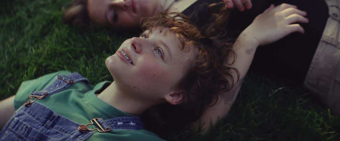 Two teenager lying on a grasslawn having a discussion at midday