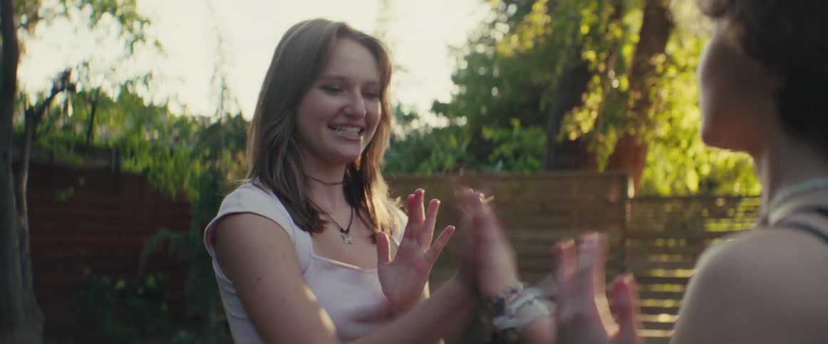 Two girls play pat a cake in the yard