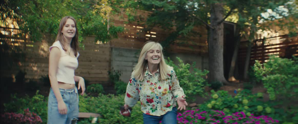Young woman and older woman play together in the garden smiling
