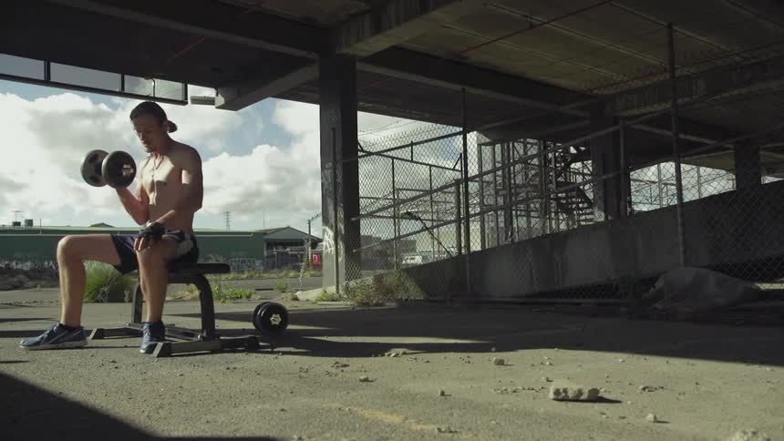 Man sitting down curls a weight
