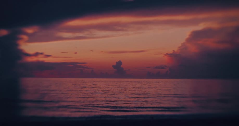 Sea horizon reflects orange and purple hues from a vivid sunset