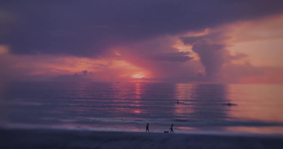 Calm sea at sunset with colorful sky and people by the shore