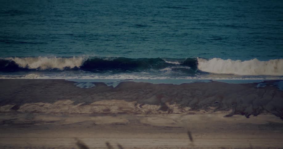 Small waves reach the sandy shore under soft light