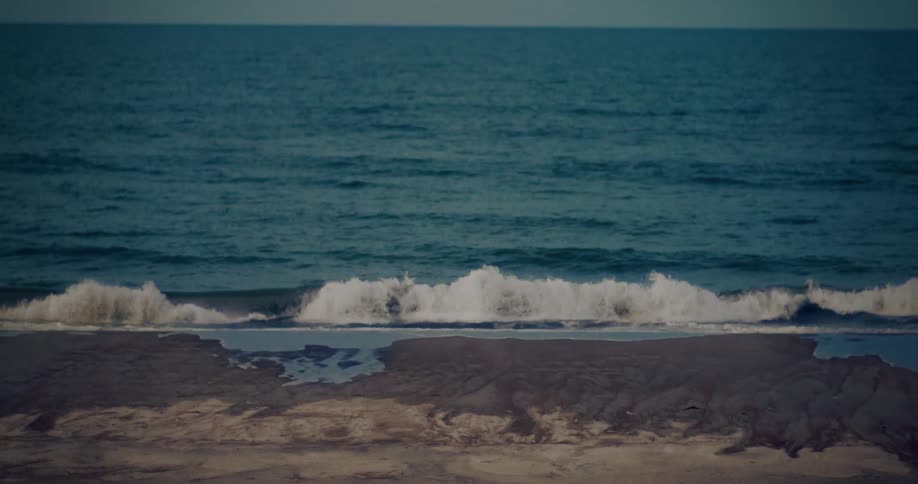 Medium waves are rolling into a coastline