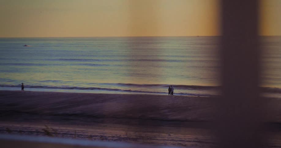 Through the window people are walking on the beach