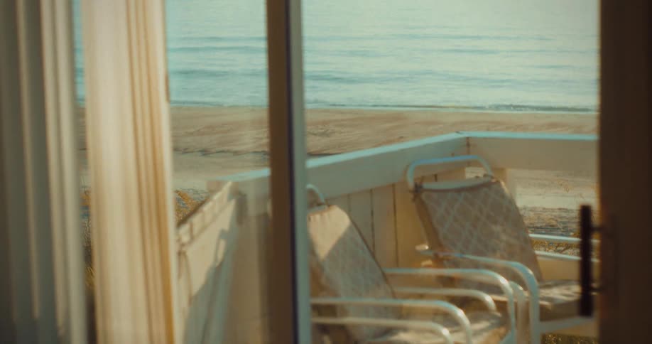 A resort balcony overlooking the beach at sunset with the ocean water visible in the distance