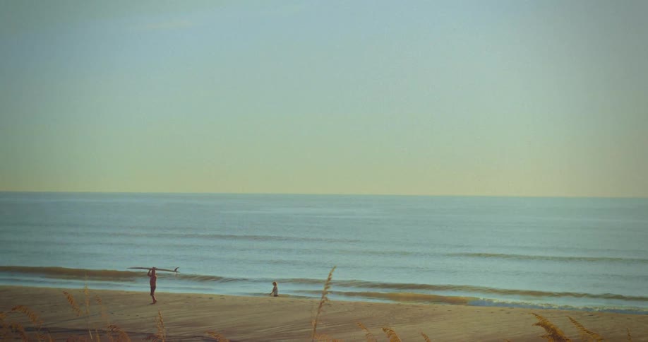 A man walks down a beach with a surfboard