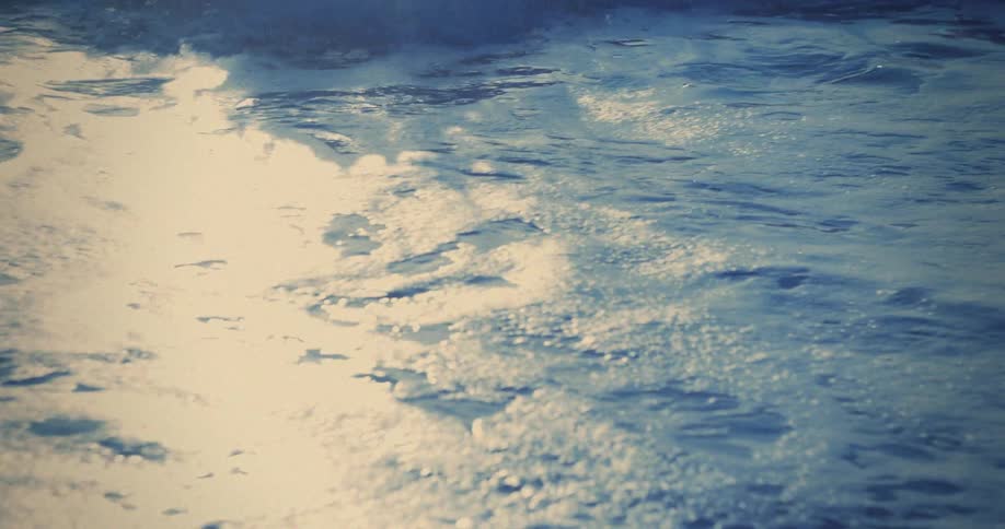 Waves crashing with bluish foam under sunlight