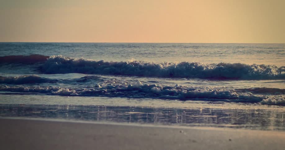 Waves gently break on the beach under the golden evening light