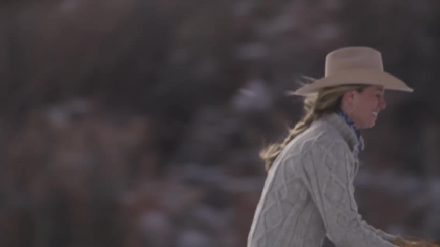 A happy young blonde woman riding her horse