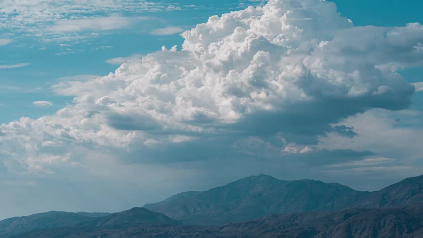 Clouds move over misty mountains during the daytime