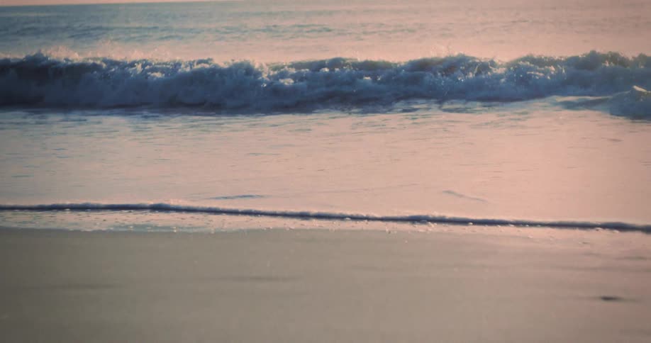 Heavy waves crash onto the beach at sunset