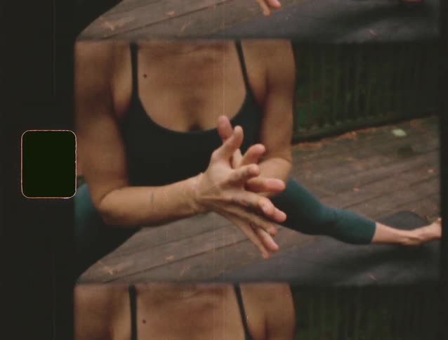 Woman in meditation pose with hands clasped at chest on outdoor deck