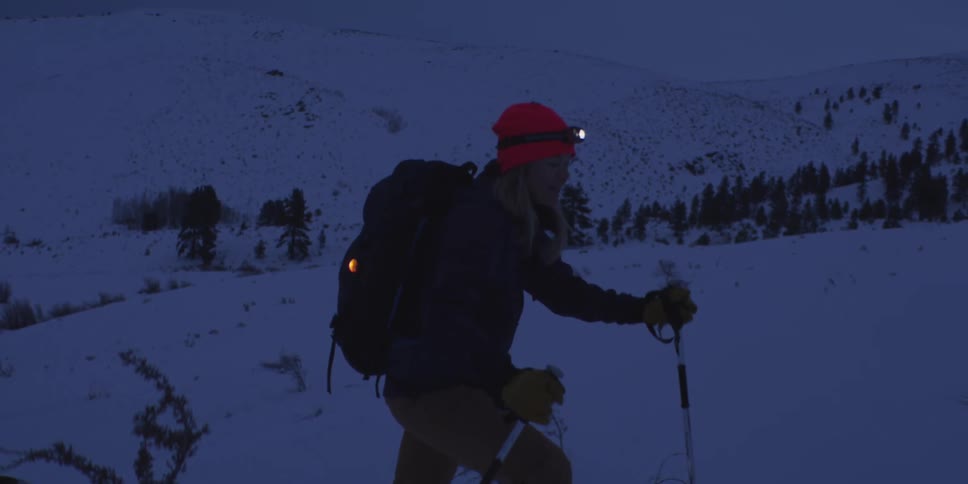 Mountaineer walking in the snow at night with a headlamp