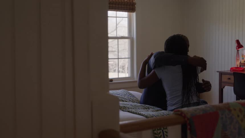 Father hugs her daughter while they sit in her bedroom on a winter day
