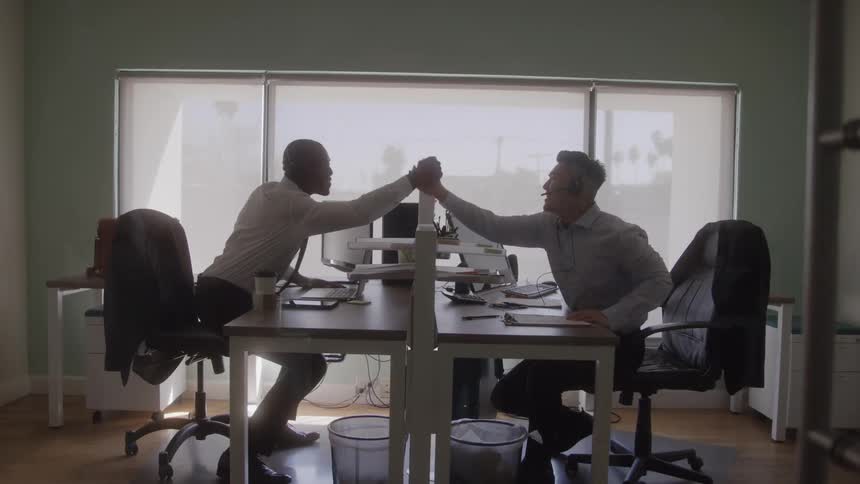 Colleagues greet each other enthusiastically while working in the office