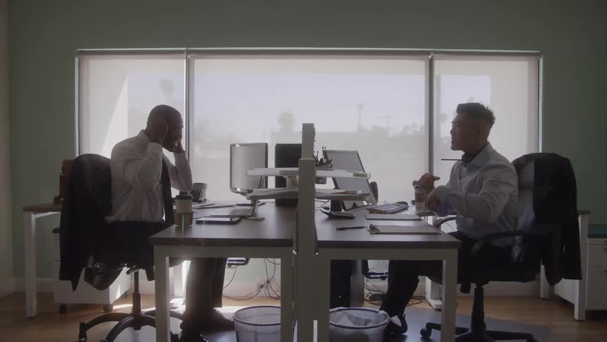 One man playfully throws a piece of paper at his fellow office coworker