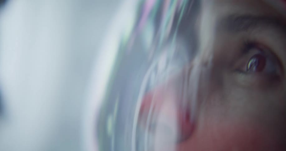 Face reflected on a space helmet visor with focus on the gaze