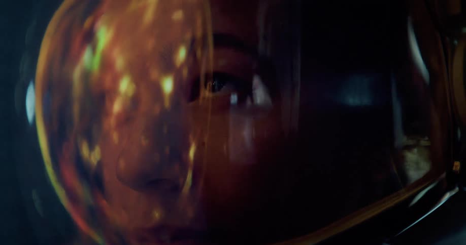 Illuminated face reflects on the golden visor of a space helmet