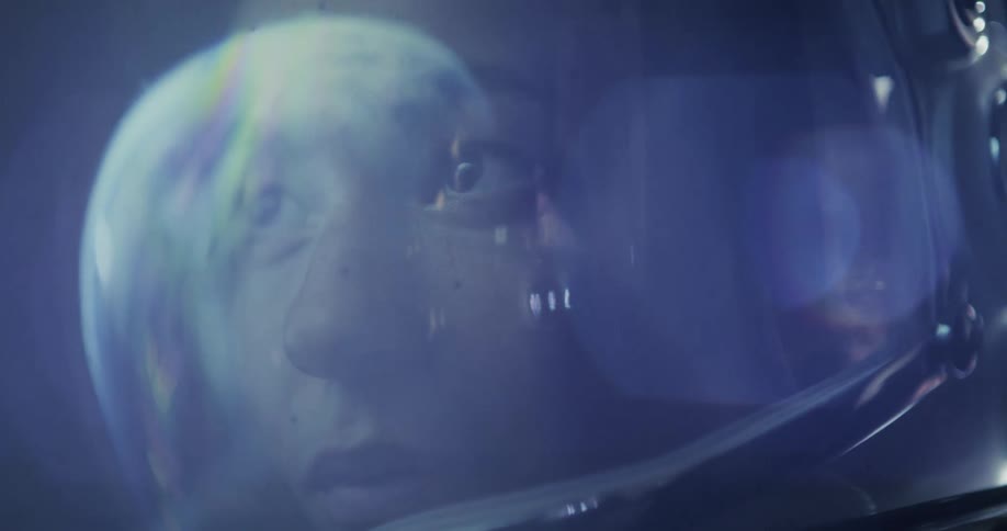 A close astronaut's face, light reflected in the clear visor