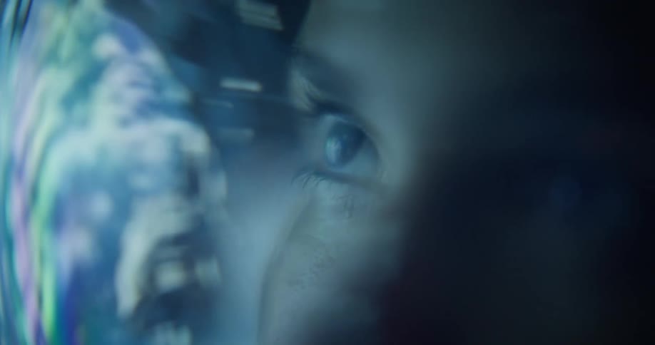 A red light and a planet are reflecting off a womans space helmet