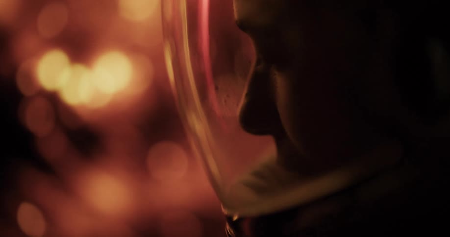 A closeup of an astronaut in silhouette with warm light reflections in the background
