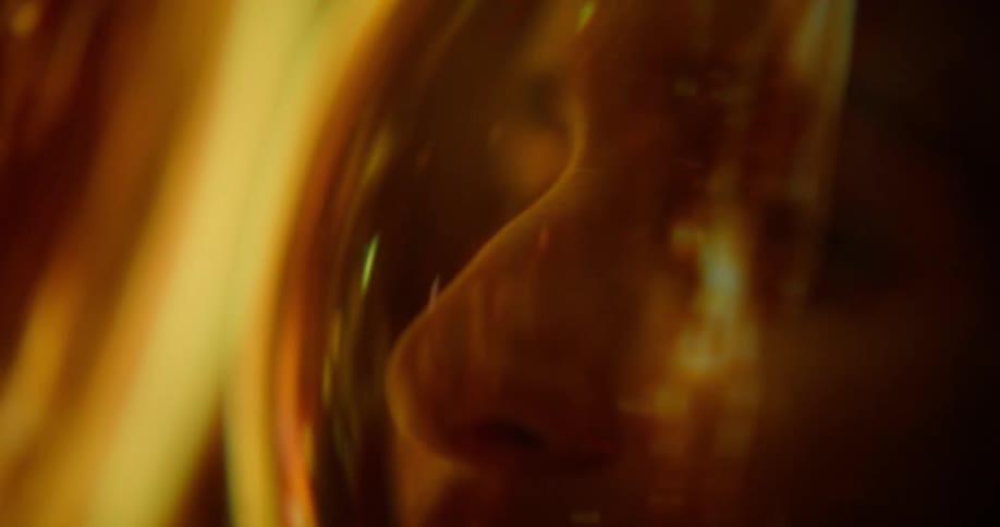 Human face behind a visor with reflected intense amber light