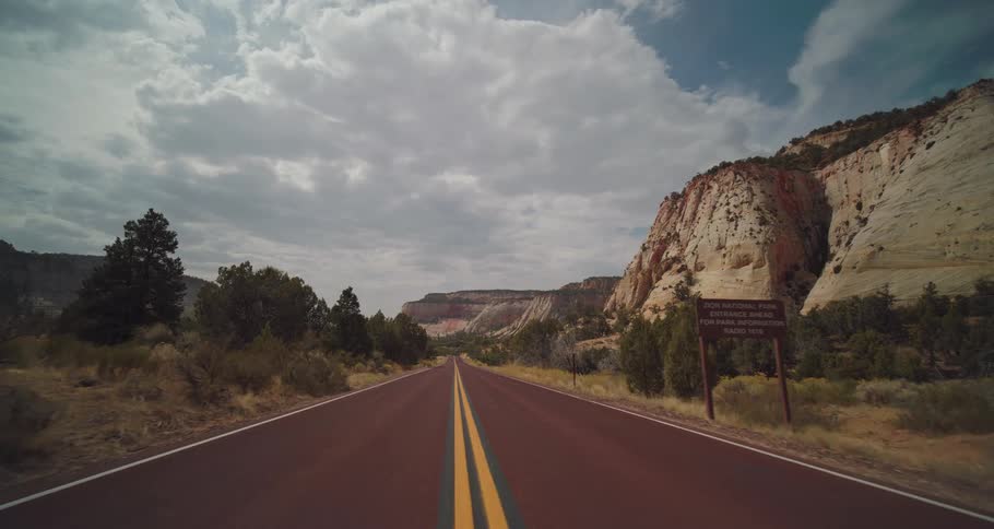 A winding road stretches through rocky desert mountains under a cloudy sky