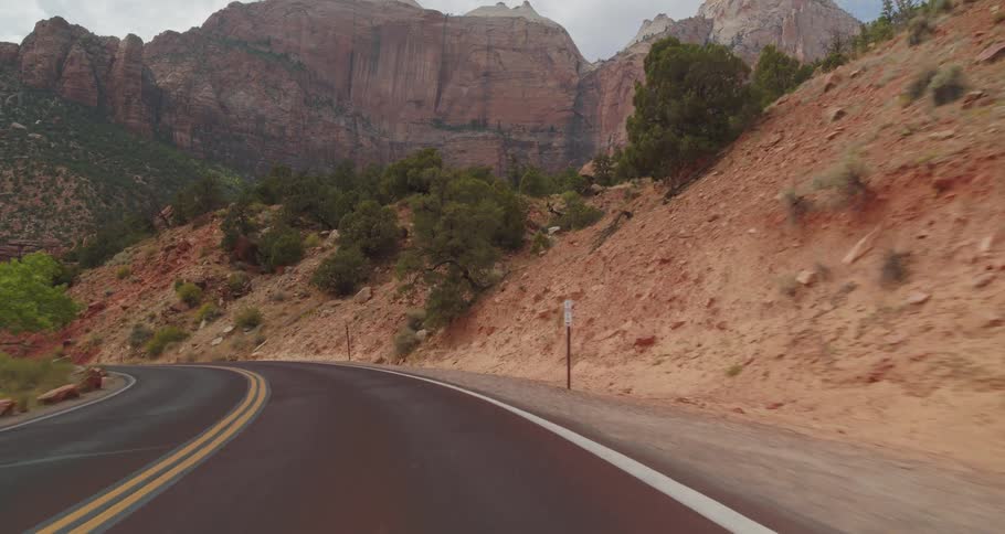 Road flanked by reddish mountains and desert vegetation