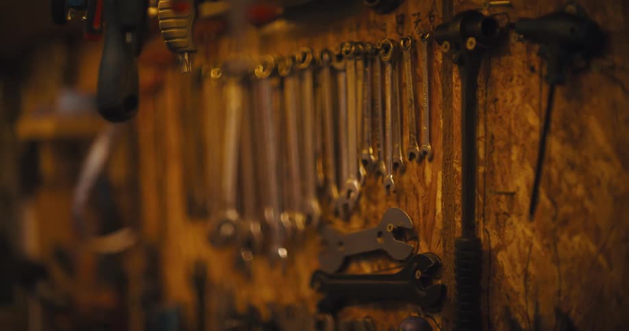 Several wrenches are hanging on a wall in a workshop
