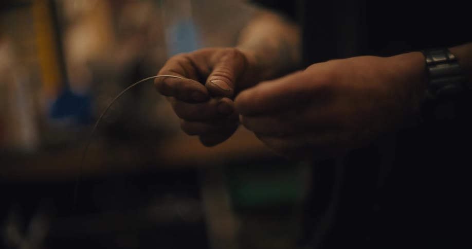 Hands hold a thin wire in a workshop setting
