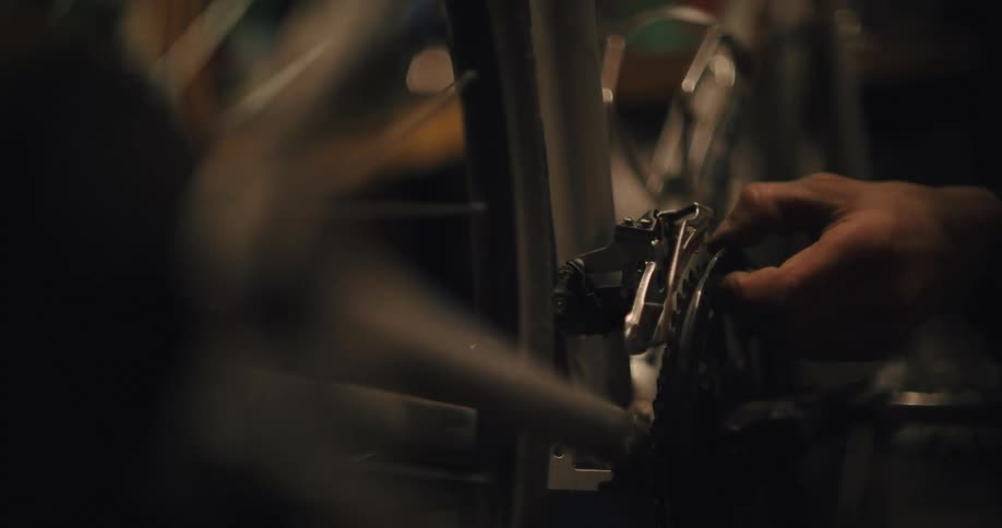 A man is moving the pedal on a bike to test the brakes