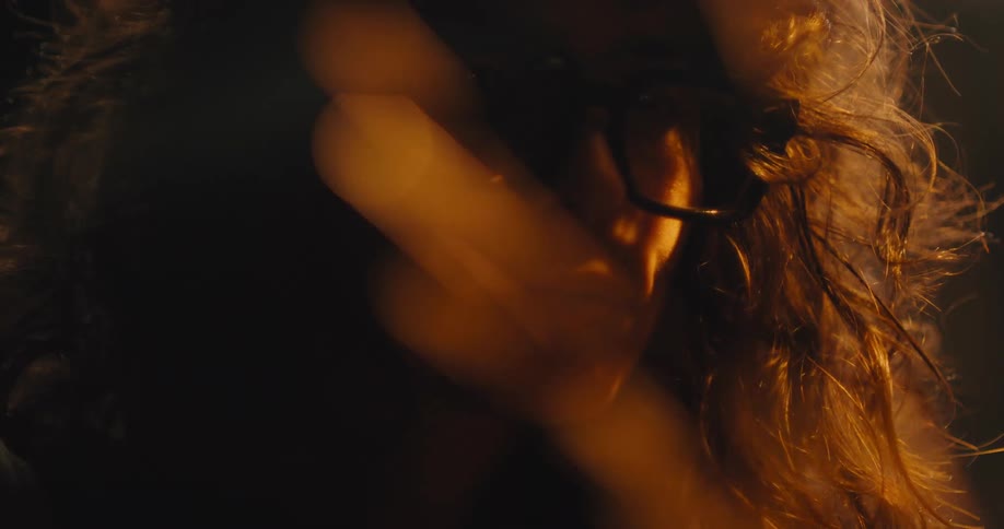 Close up as sparks fly in the foreground of a woman using an angle grinder