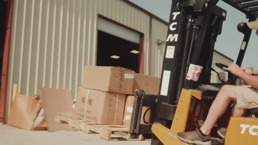 Operator drives a forklift moving boxes in an industrial area