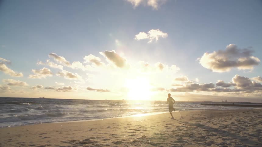 Man jogging on a beach at sunset