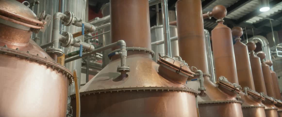 Copper distillation columns connected by valves and metal pipes in an industrial setting