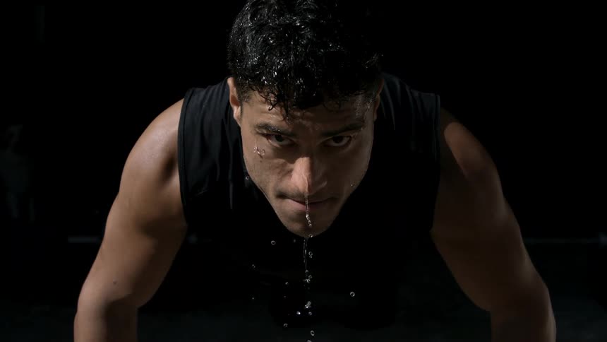 Sweat drips from a mans face as he does push ups