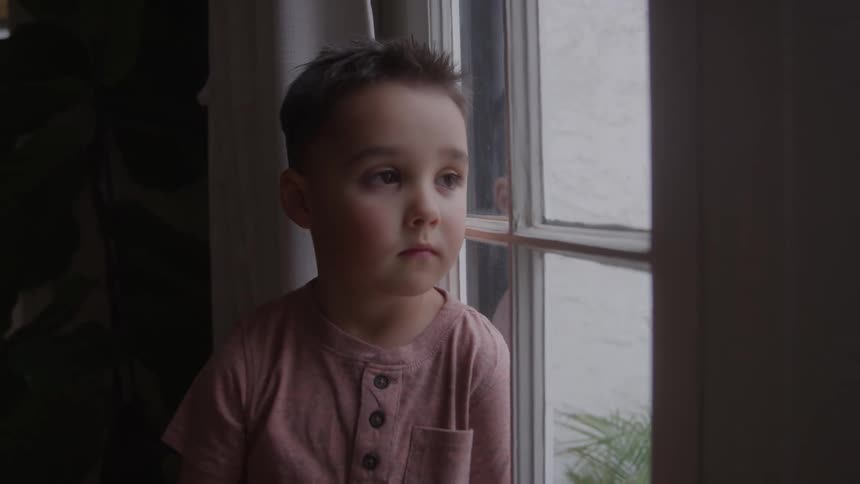 The child is sitting by the window